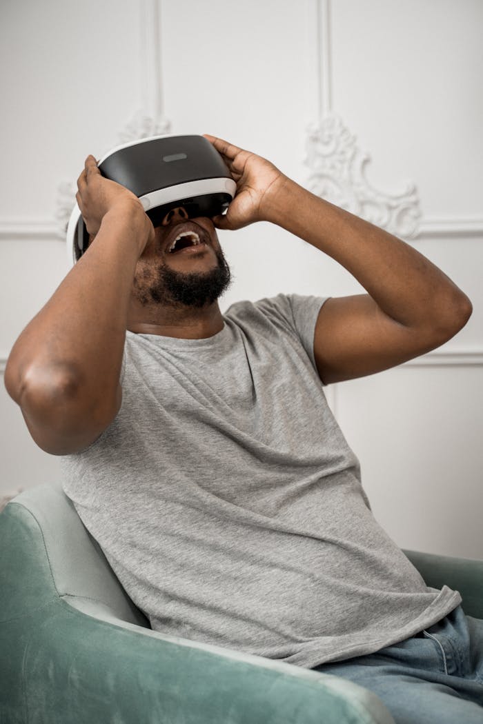 Adult man seated indoors experiencing virtual reality with VR glasses, wearing casual attire.
