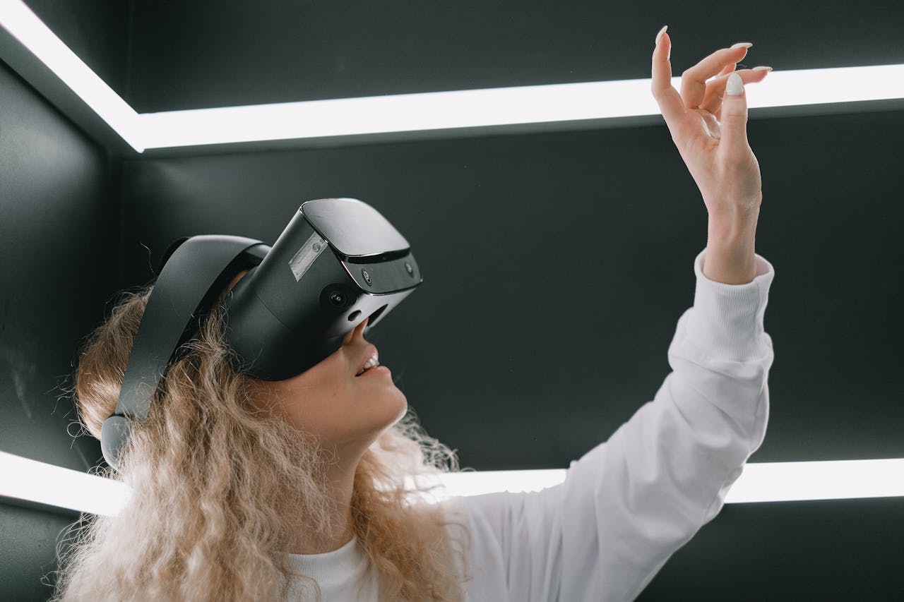Services-02 A woman wearing a headset engages with virtual reality, reaching out her hand.